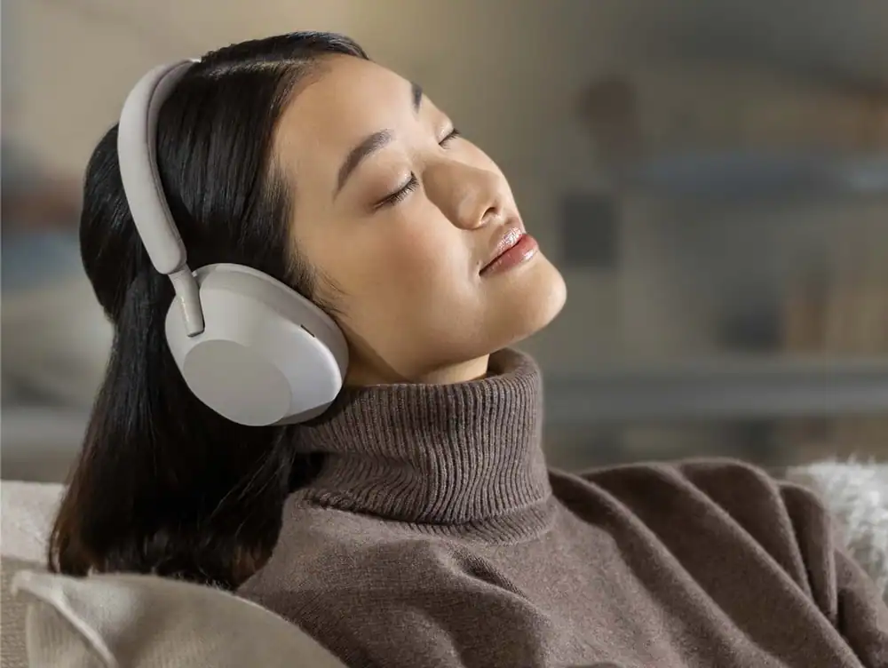 Relaxed woman with headphones enjoying music, representing comfort and focus in hybrid work environm.