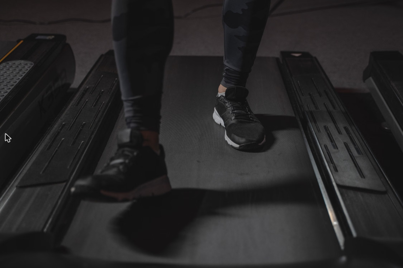 Under desk walking pad treadmill beside a home office standing desk